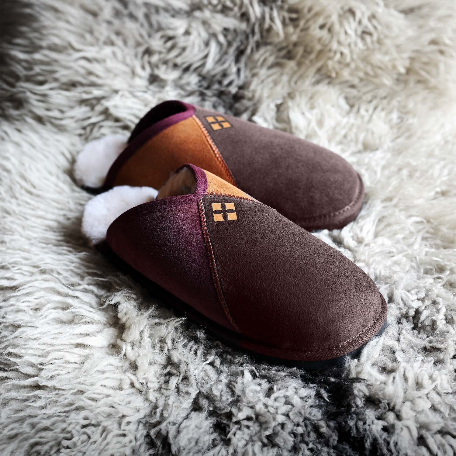A pair of sheepskin slippers on a sheepskin rug.