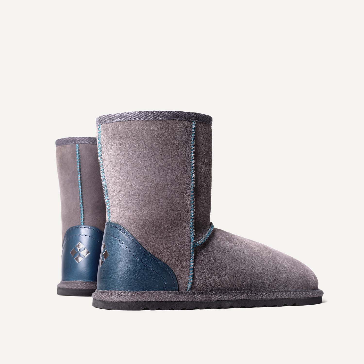 A pair of grey slipper boots with teal leather heels.