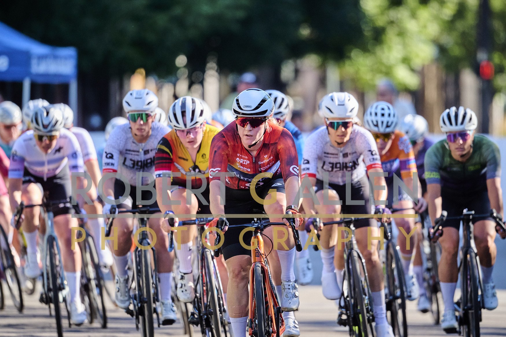 A group of cyclists racing on a street, wearing helmets and colorful jerseys, focused on the race.