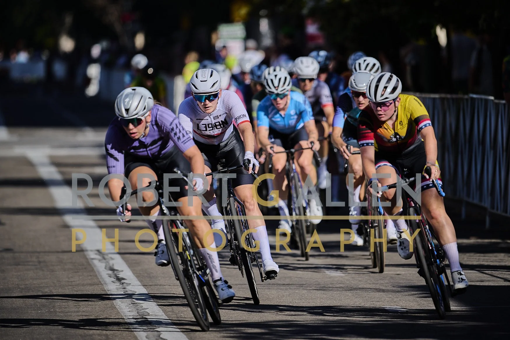 Cyclists participating in a race, riding on a city street with barriers on the side