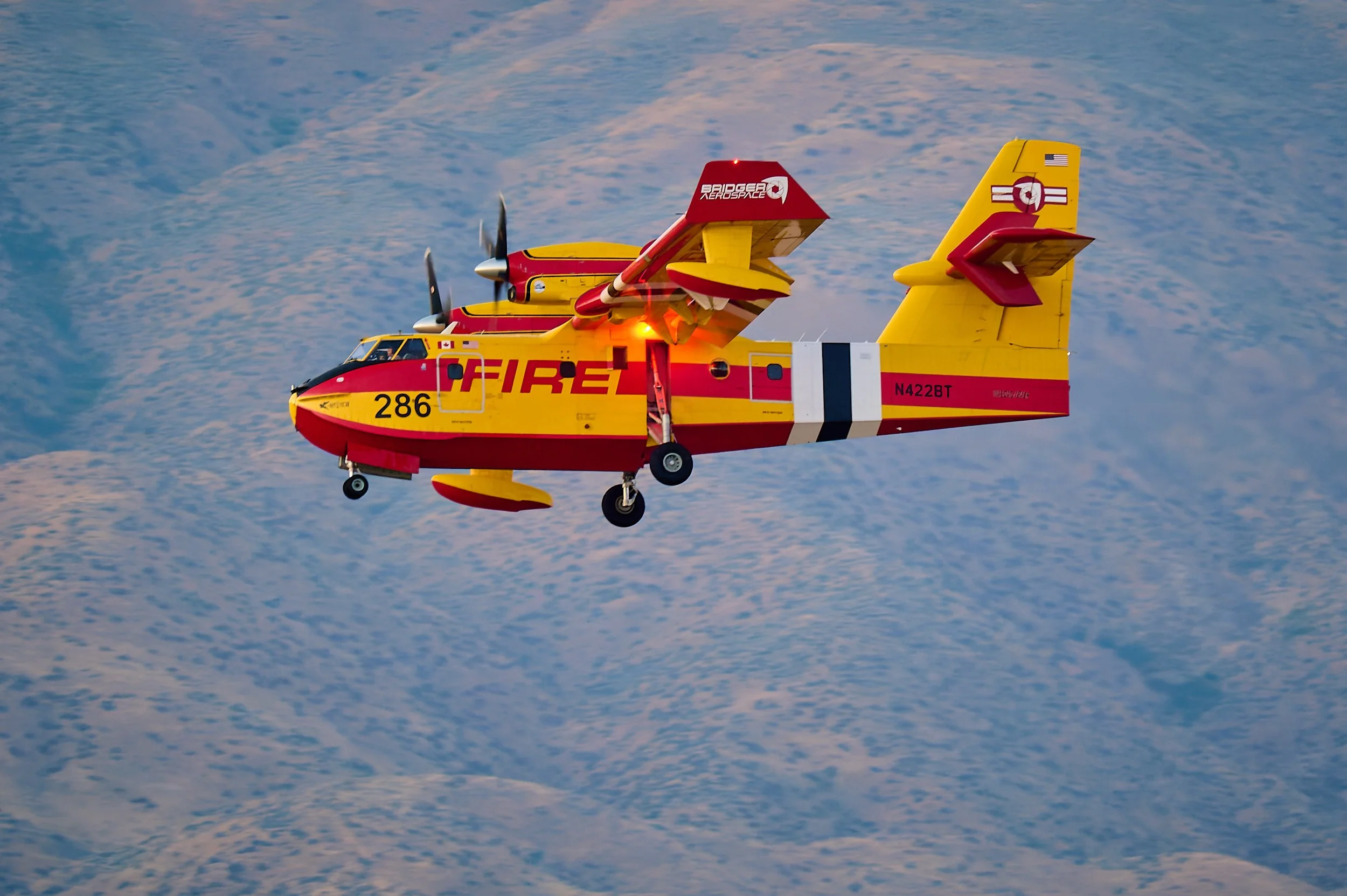 Colorful rescue helicopter flying over snow-covered mountains.