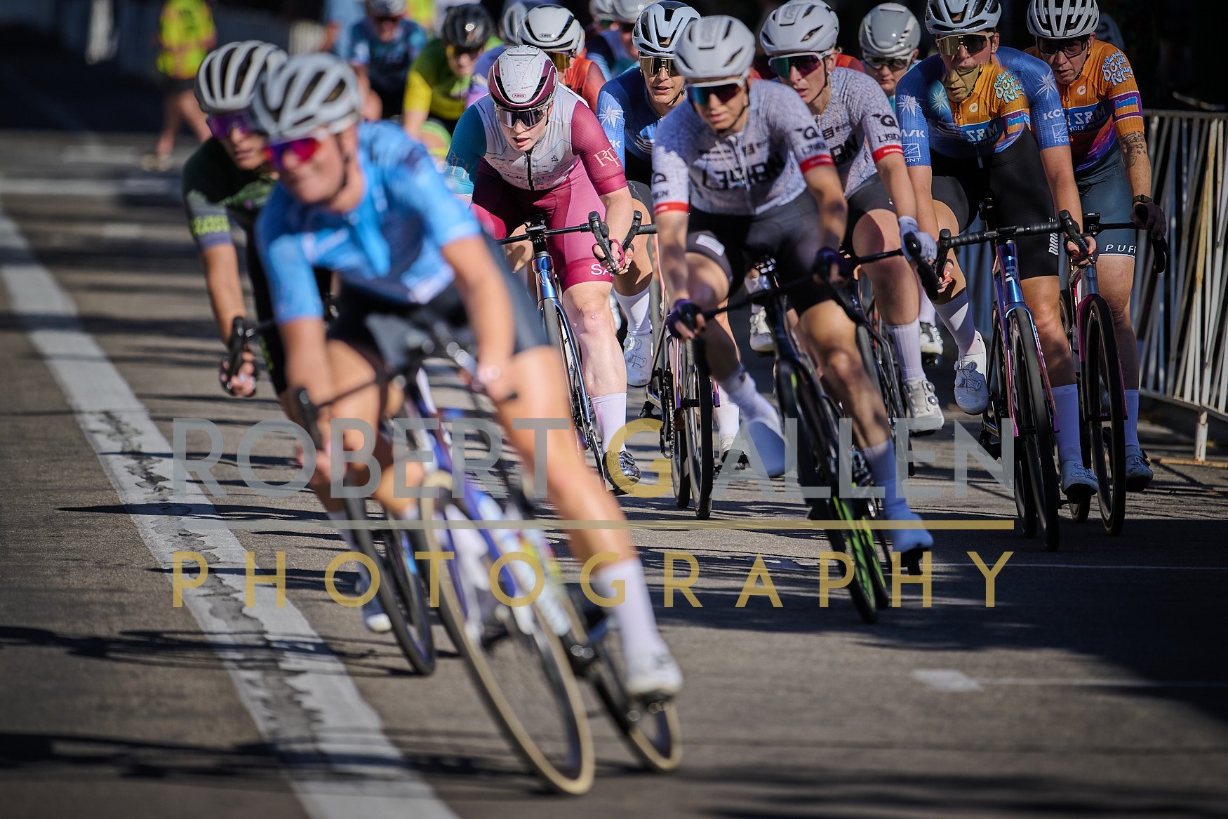 A group of cyclists racing on a track, wearing helmets and sports gear.