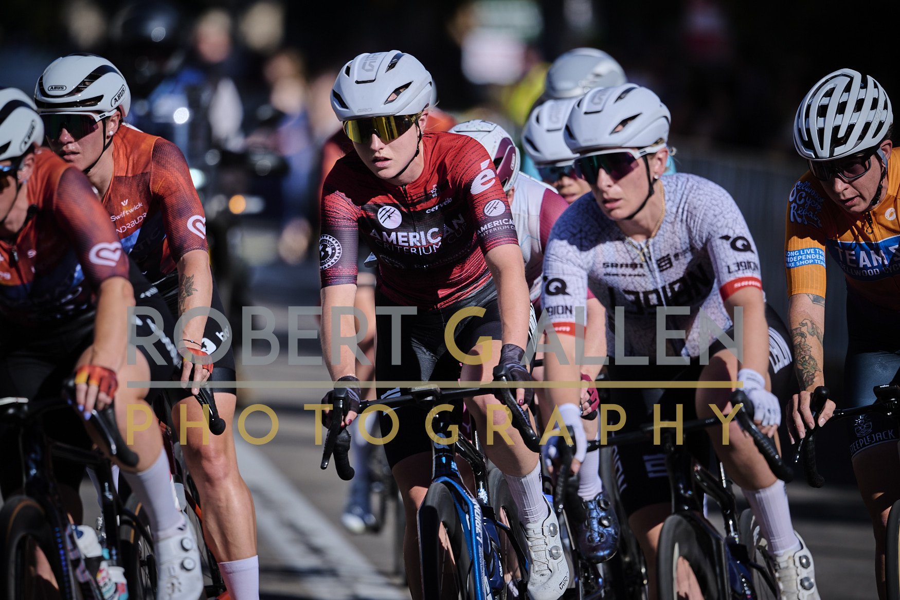 Cyclists wearing helmets and sportswear riding in a race, with focus on their faces and bikes.