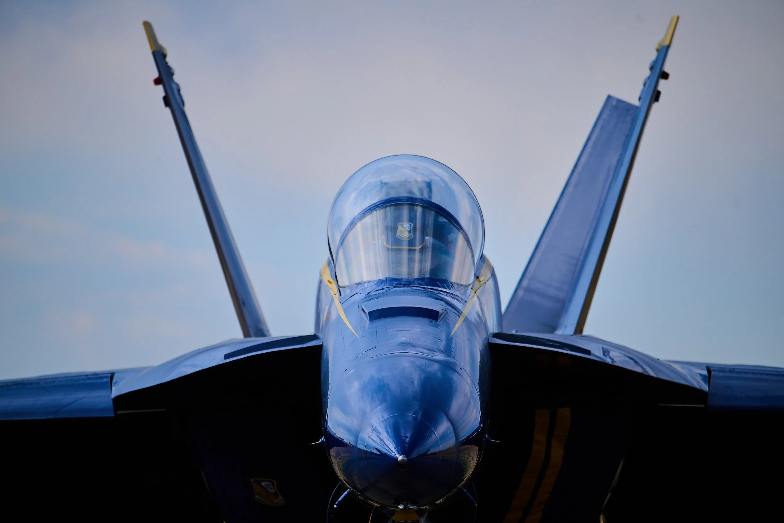 Looking up at a fighter jet nose with blue sky in background.