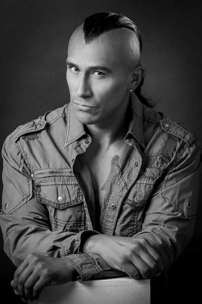 Black and white portrait of American Indian posing in the studio with mohawk haircut.