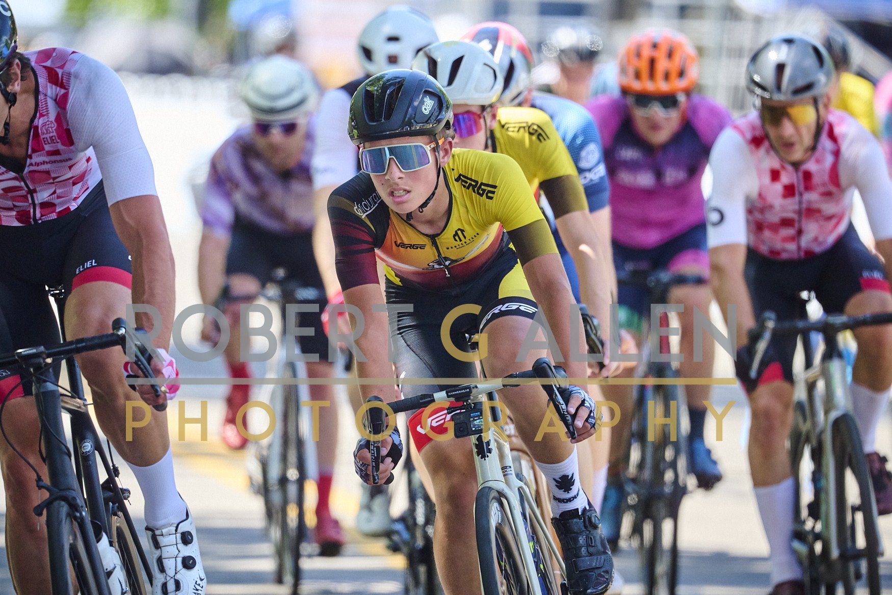 A group of cyclists racing in a competitive biking event, wearing colorful jerseys and helmets, focused on the race.
