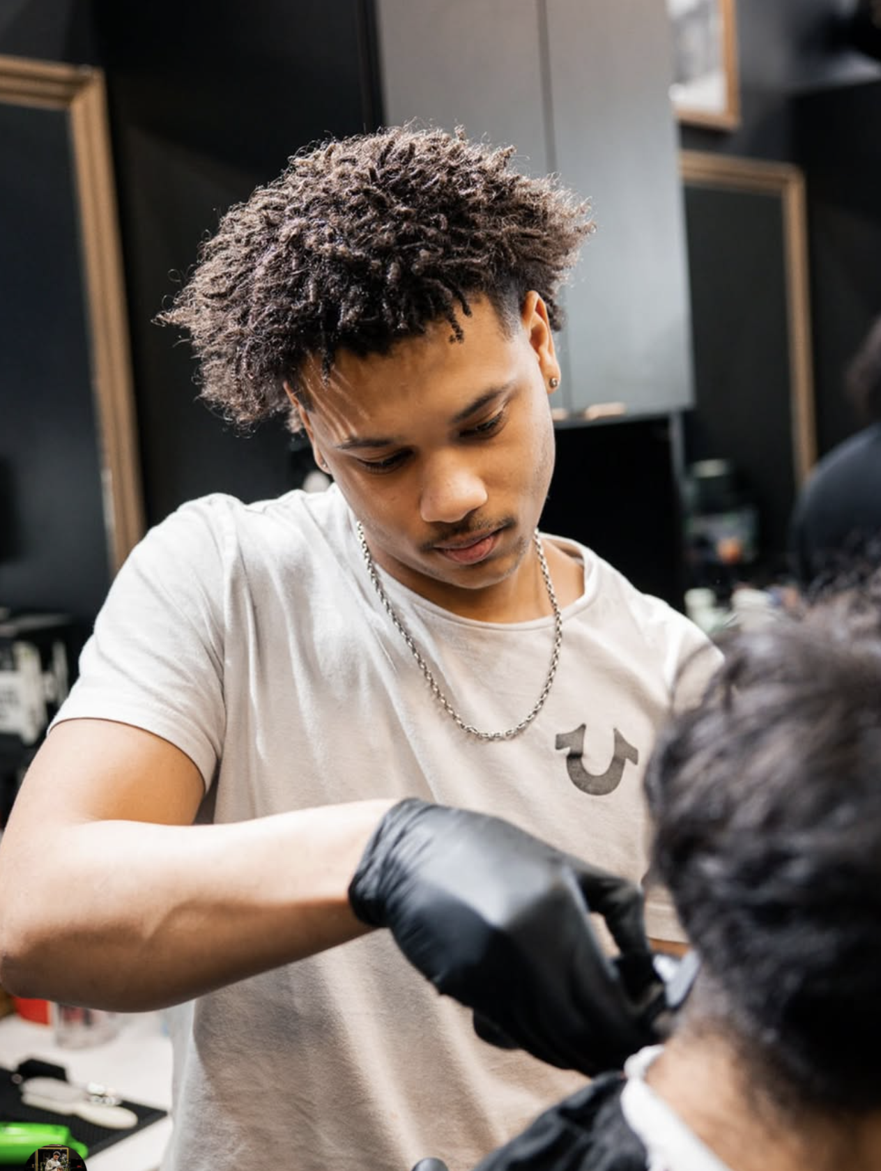 A barber cutting a male client's hair in a barbershop.