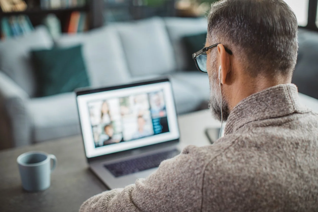 A man at home talking with his clinician over a laptop video call