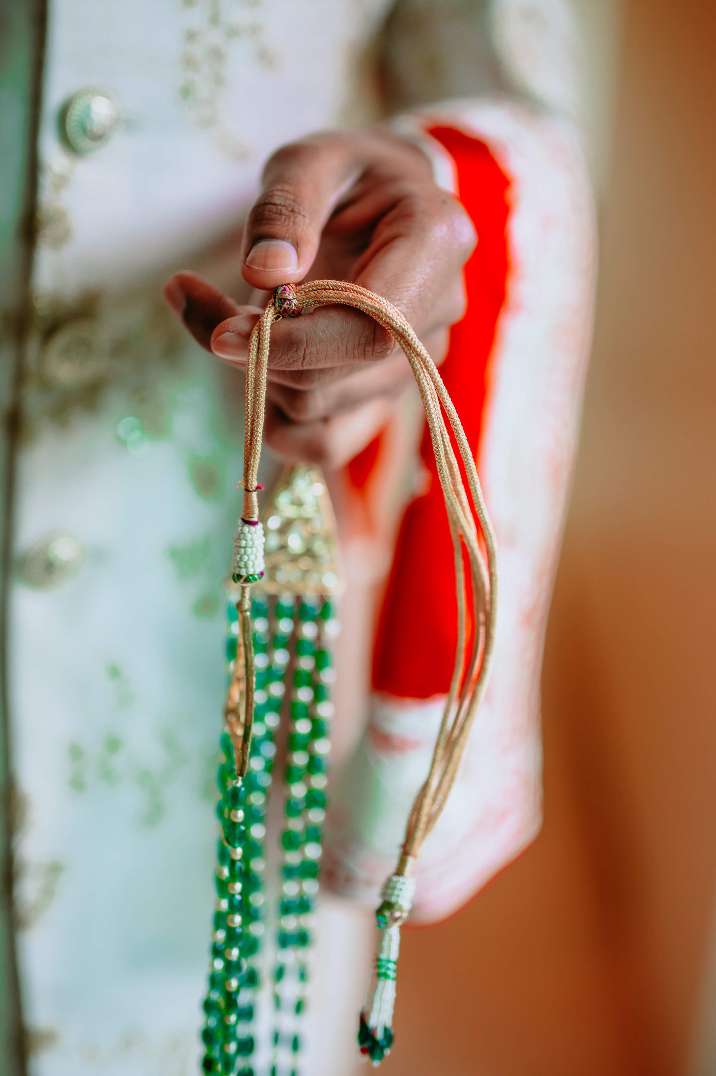 A person holding multiple colorful beaded necklaces in front of a decorated door.