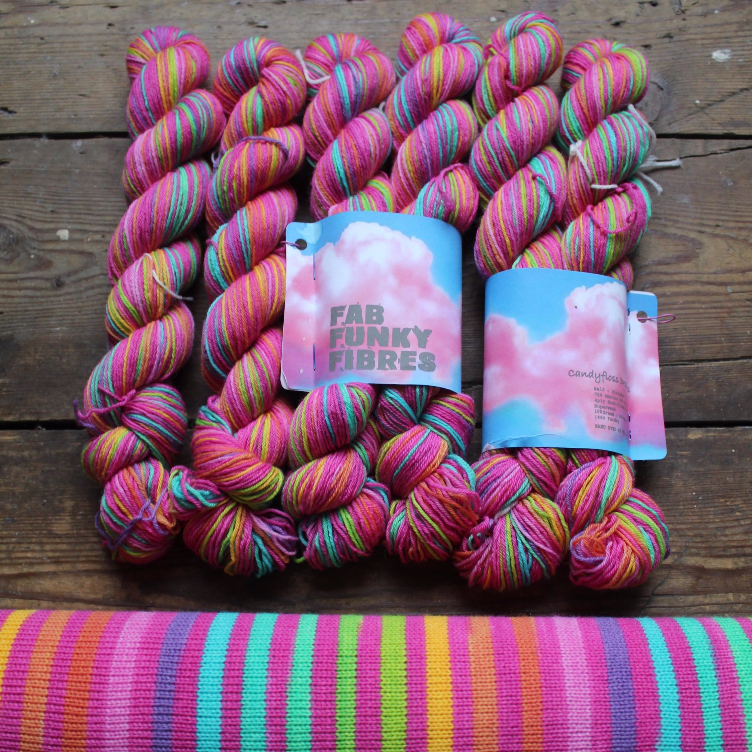 20 striped hand dyed self-striping yarn in lushes timeless rainbow colours separated by a candy pink stripe