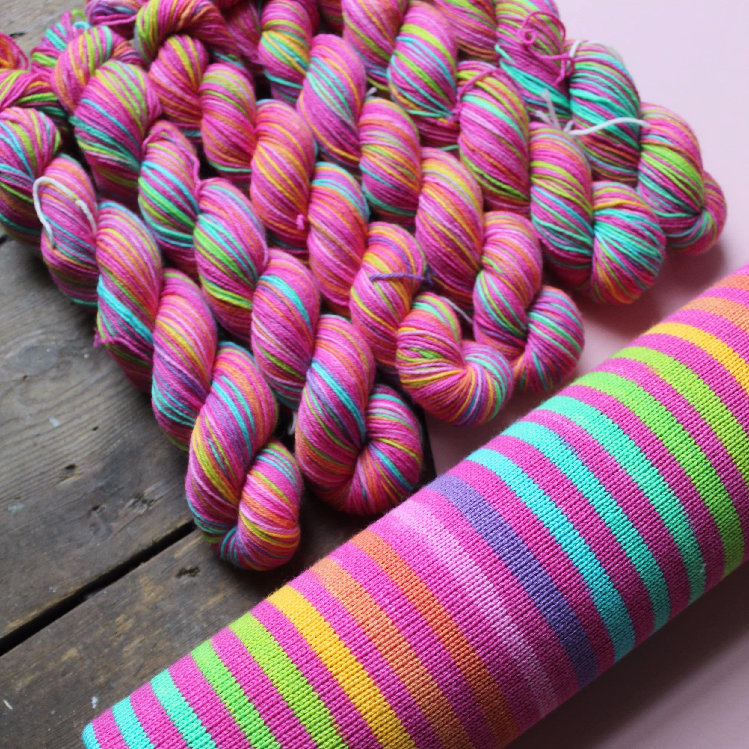 20 striped hand dyed self-striping yarn in lushes timeless rainbow colours separated by a candy pink stripe