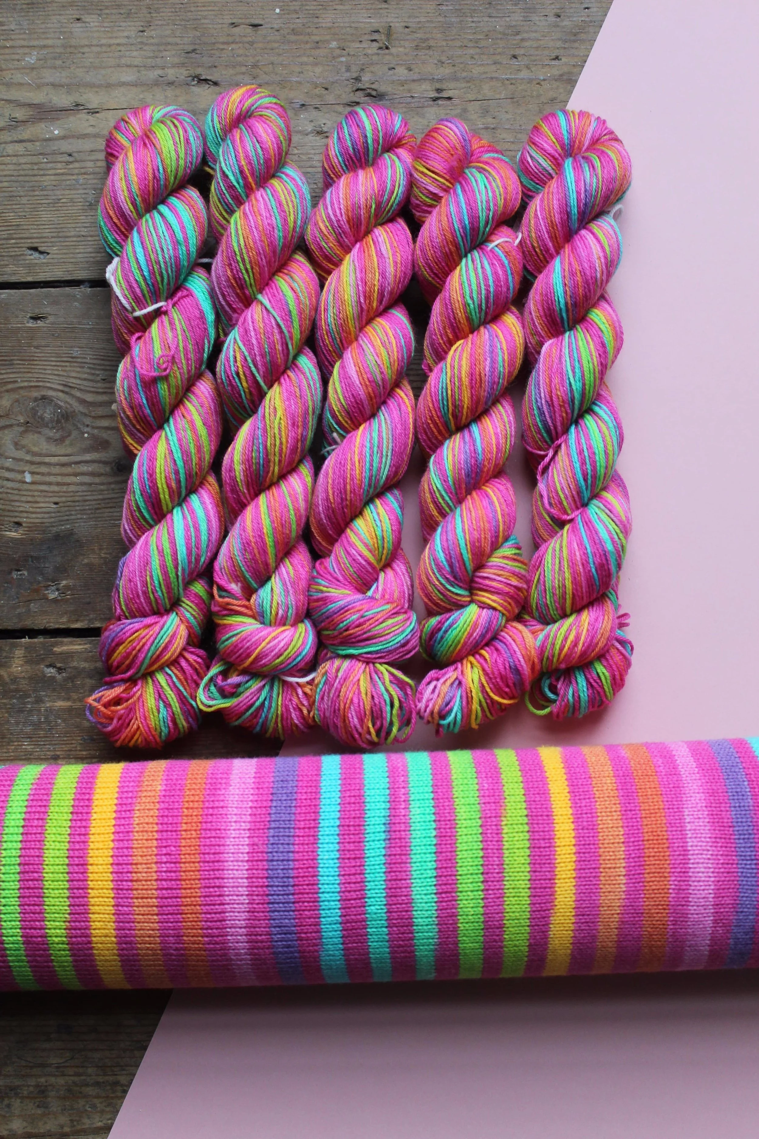 20 striped hand dyed self-striping yarn in lushes timeless rainbow colours separated by a candy pink stripe