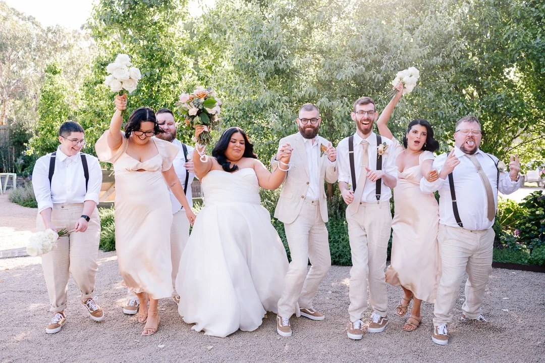 A group of people celebrating at a wedding, holding flowers and smiling outdoors.