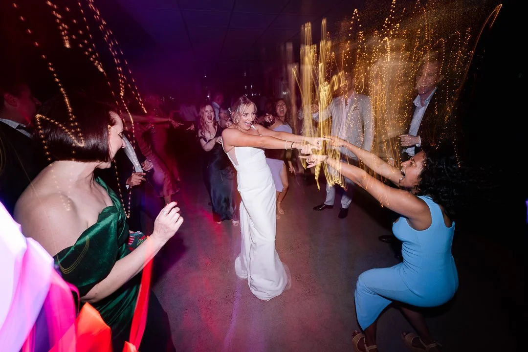 People dancing and celebrating at a party with sparklers and colorful lights.