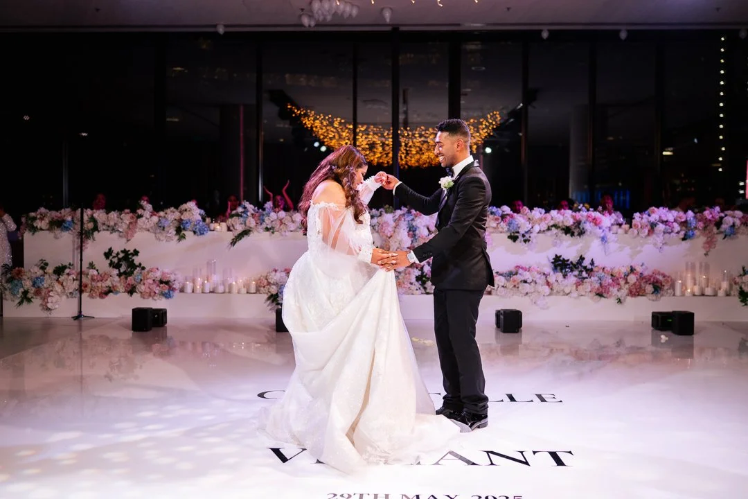 Bride and groom dancing at their wedding reception with floral decorations and candles in the background.
