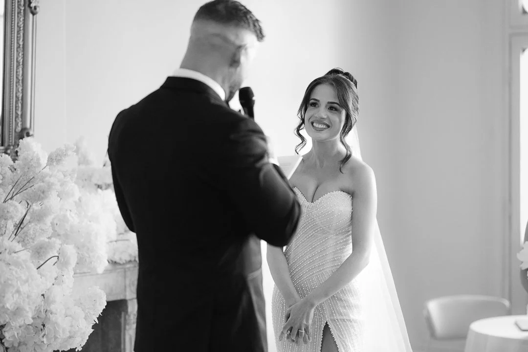 A bride smiling at a groom during a wedding ceremony.