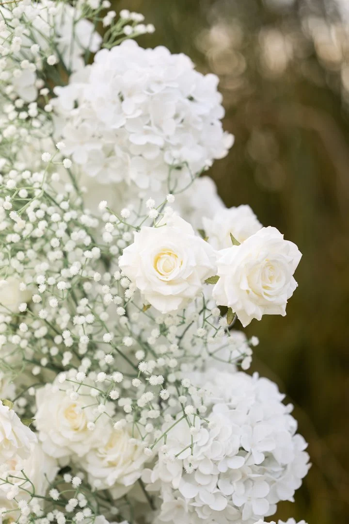 Close-up of white hydrangea, roses, and baby's breath flowers in a bouquet.