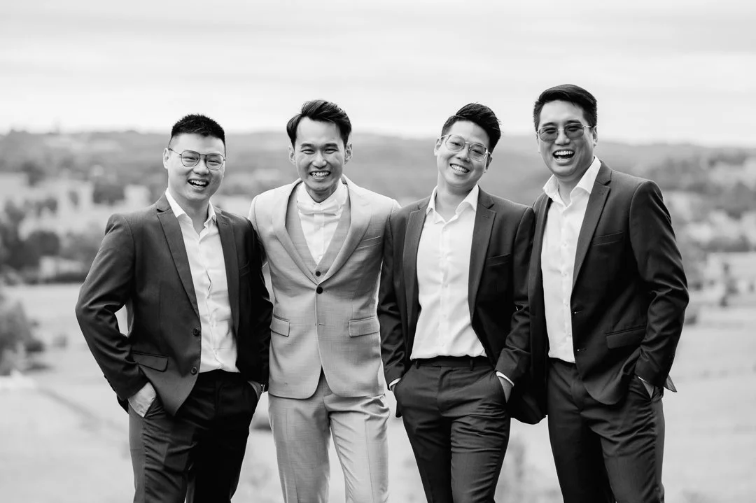 Four men in suits standing outdoors, smiling at the camera.
