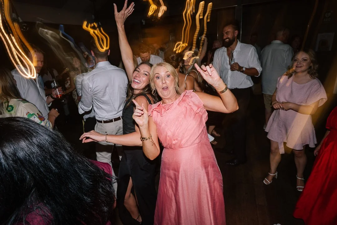 People dancing and having fun at a party or celebration, with colorful lights and a lively atmosphere.