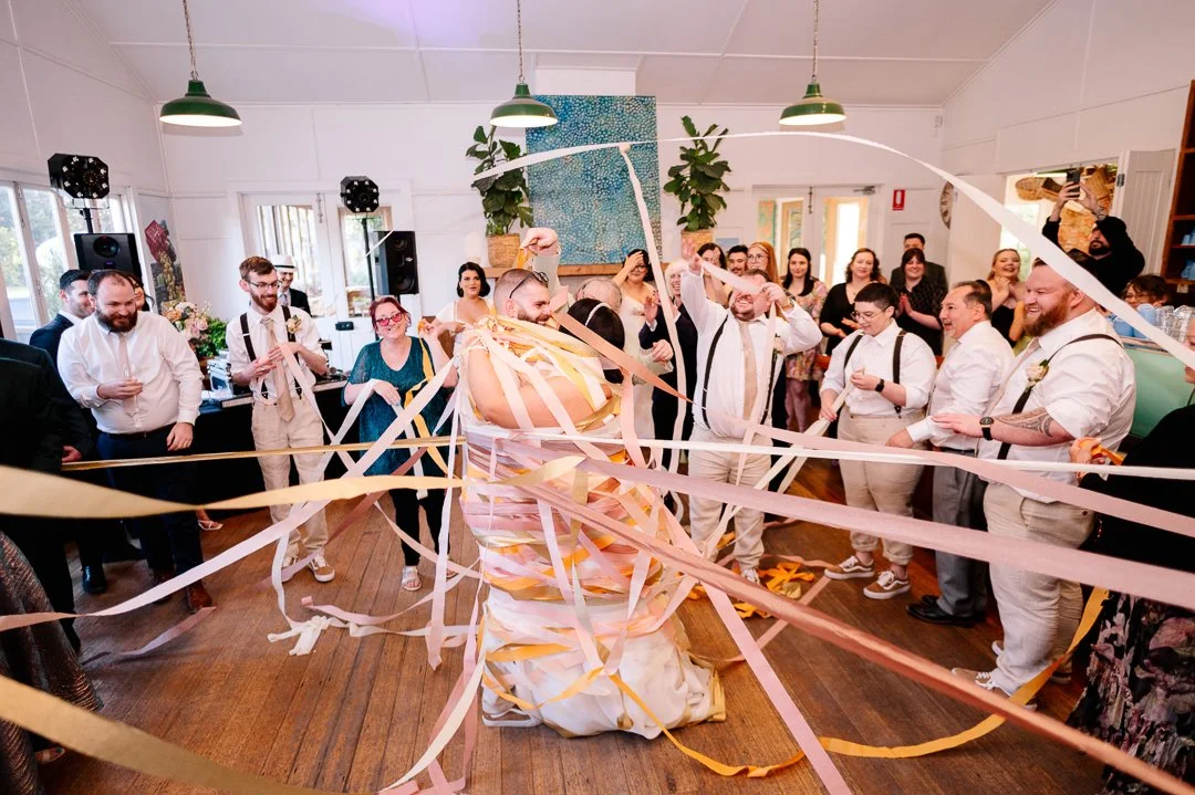 People at a celebration dance with streamers in a decorated indoor space.