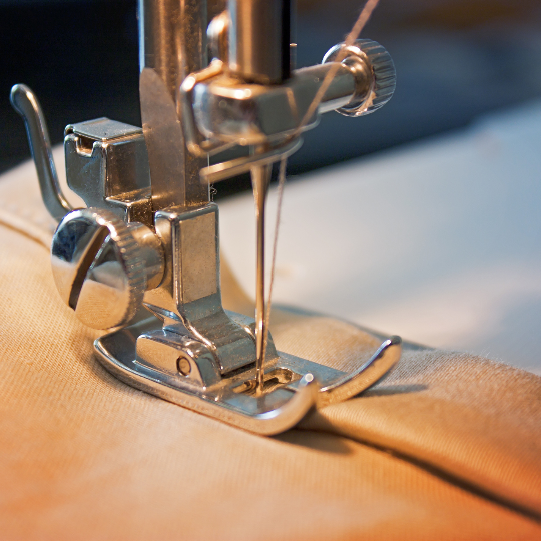 Close-up of a sewing machine needle with fabric being sewn.