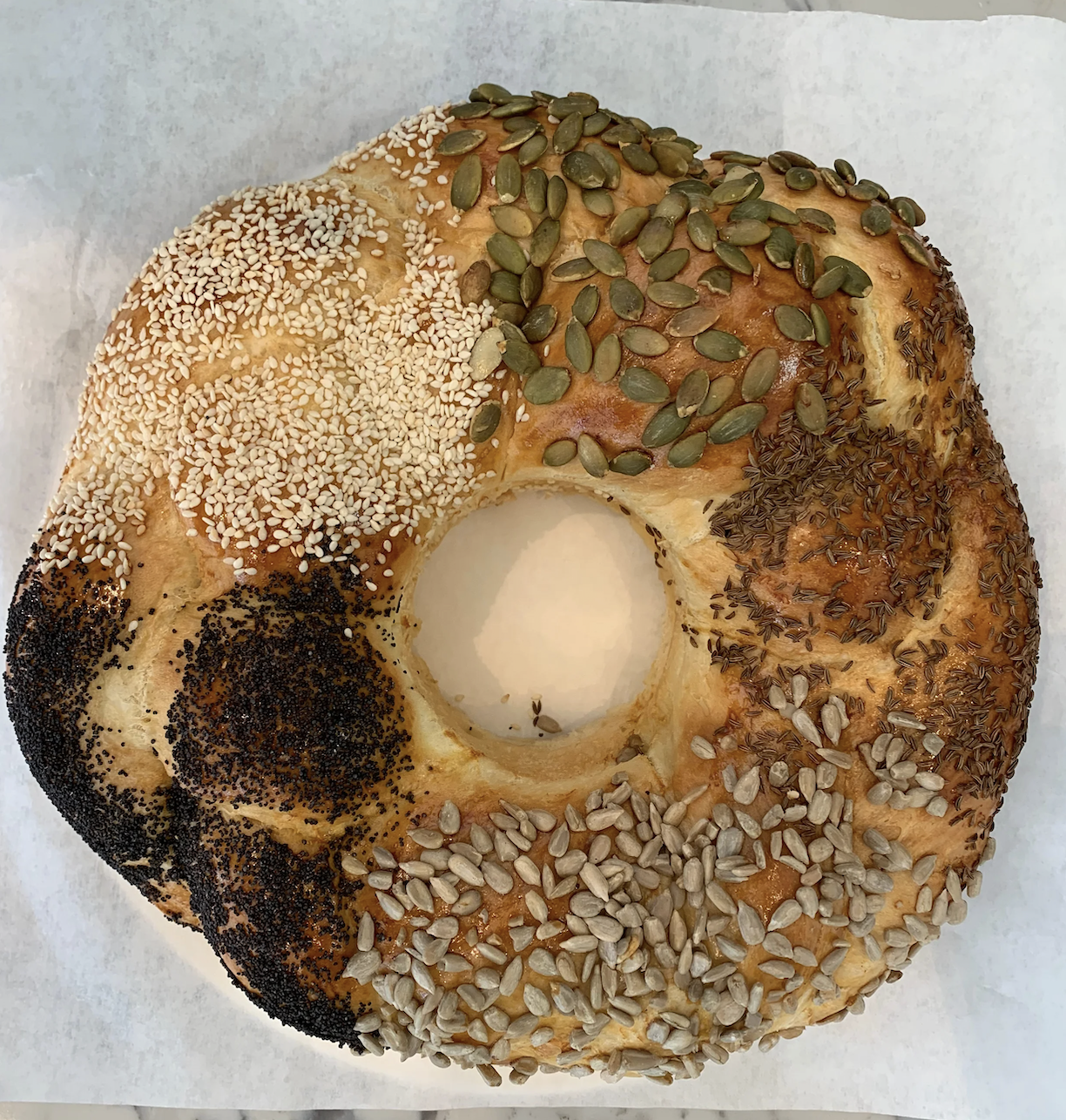 a round, braided challah topped with sesame, pumpkin seeds, sunflower seeds, poppy and caraway seeds.