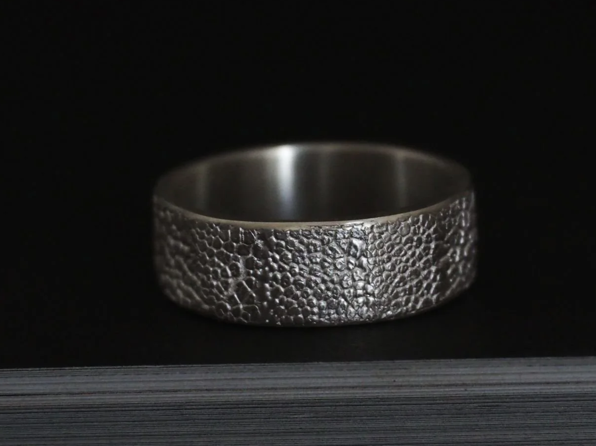 Bague empreinte de truffe de chien en argent sur fond noir.