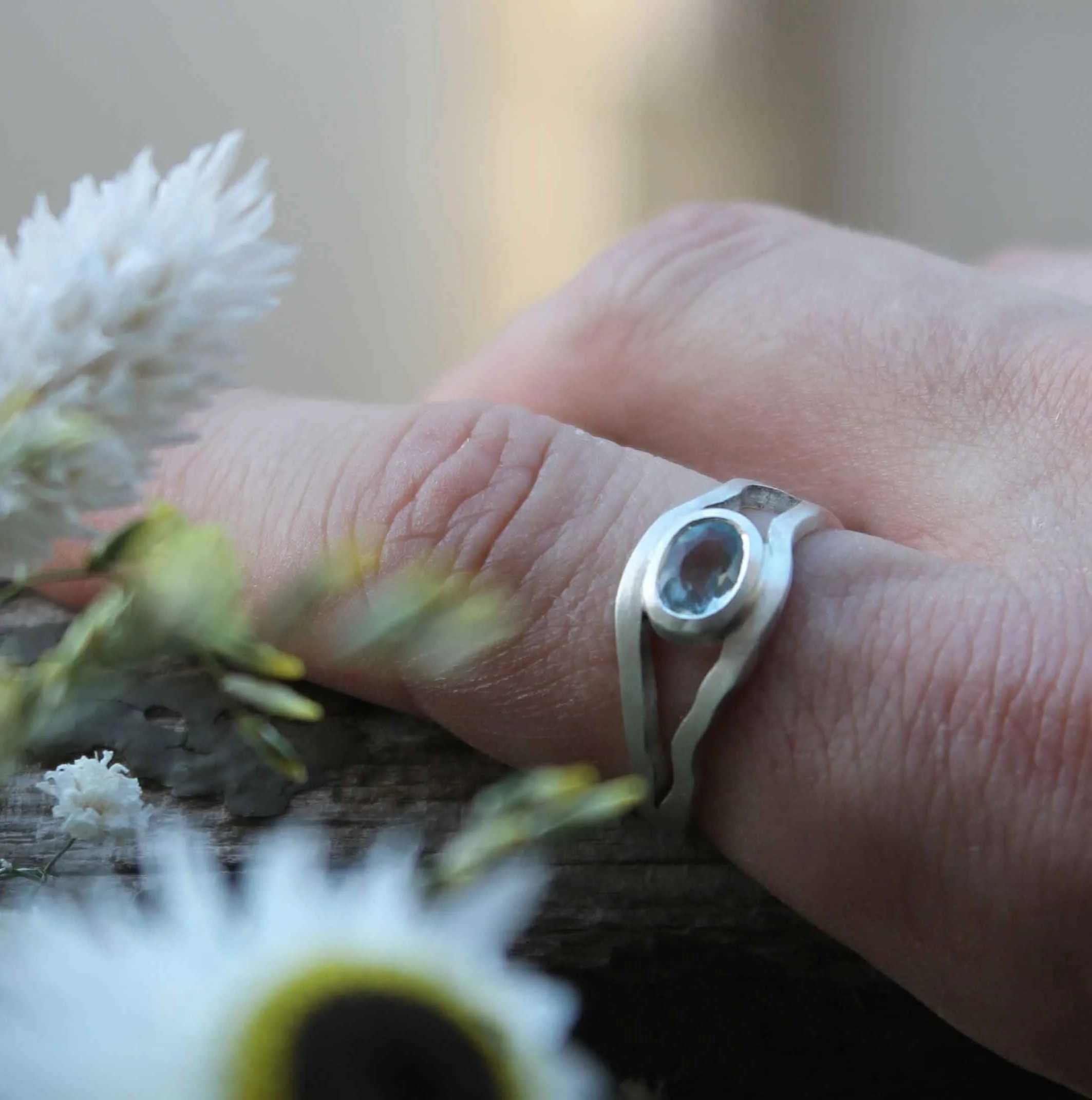 Création de bague sur mesure en ligne. Bague en argent sertie d’une aigue-marine entourée de fleurs.