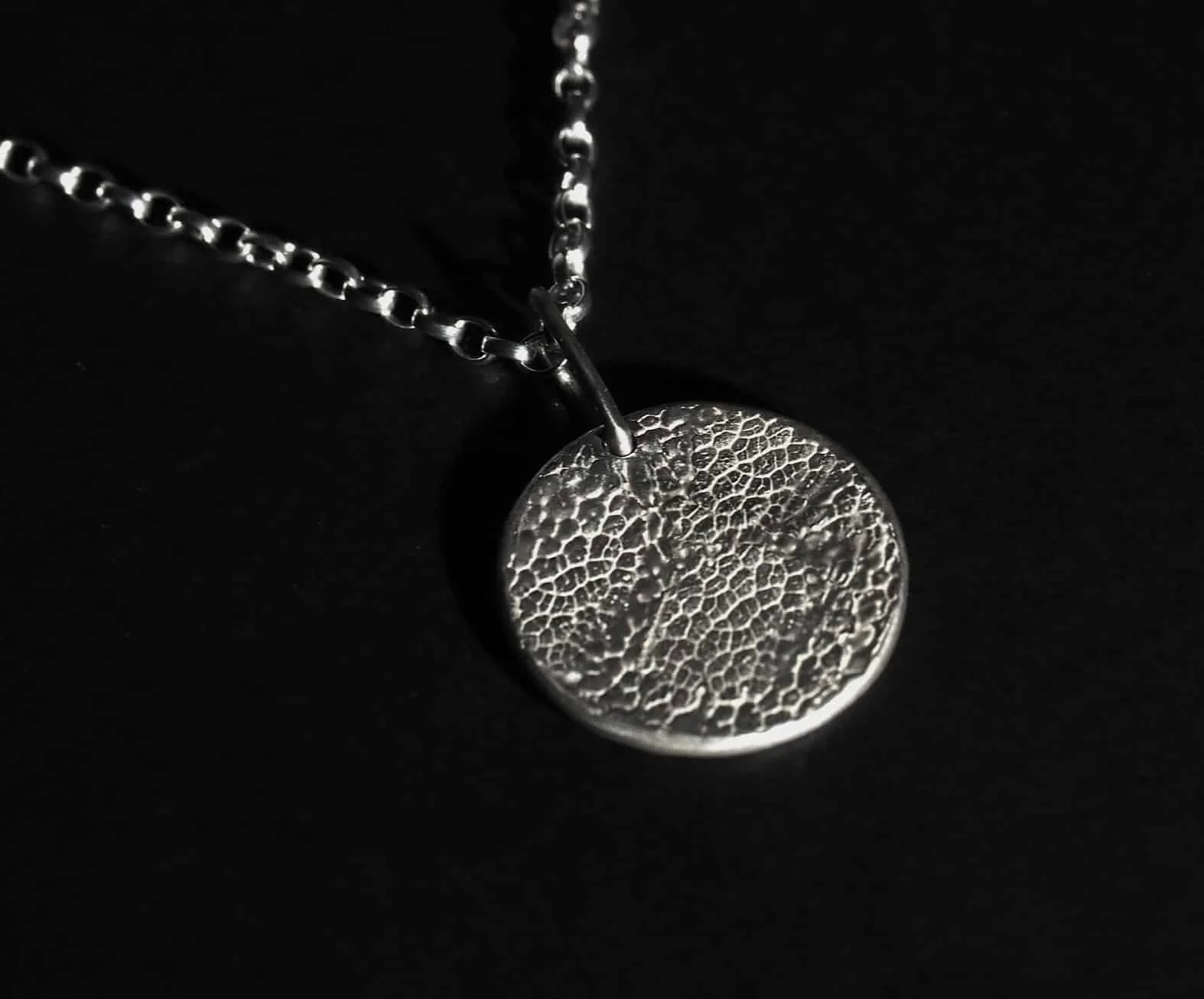 pendentif empreinte de chien sous forme de médaillon rond sur fond noir. Ce collier truffe de chien est en argent 925 avec des finitions mates. Le médaillon est recouvert de l’empreinte de la truffe d’un chien.
