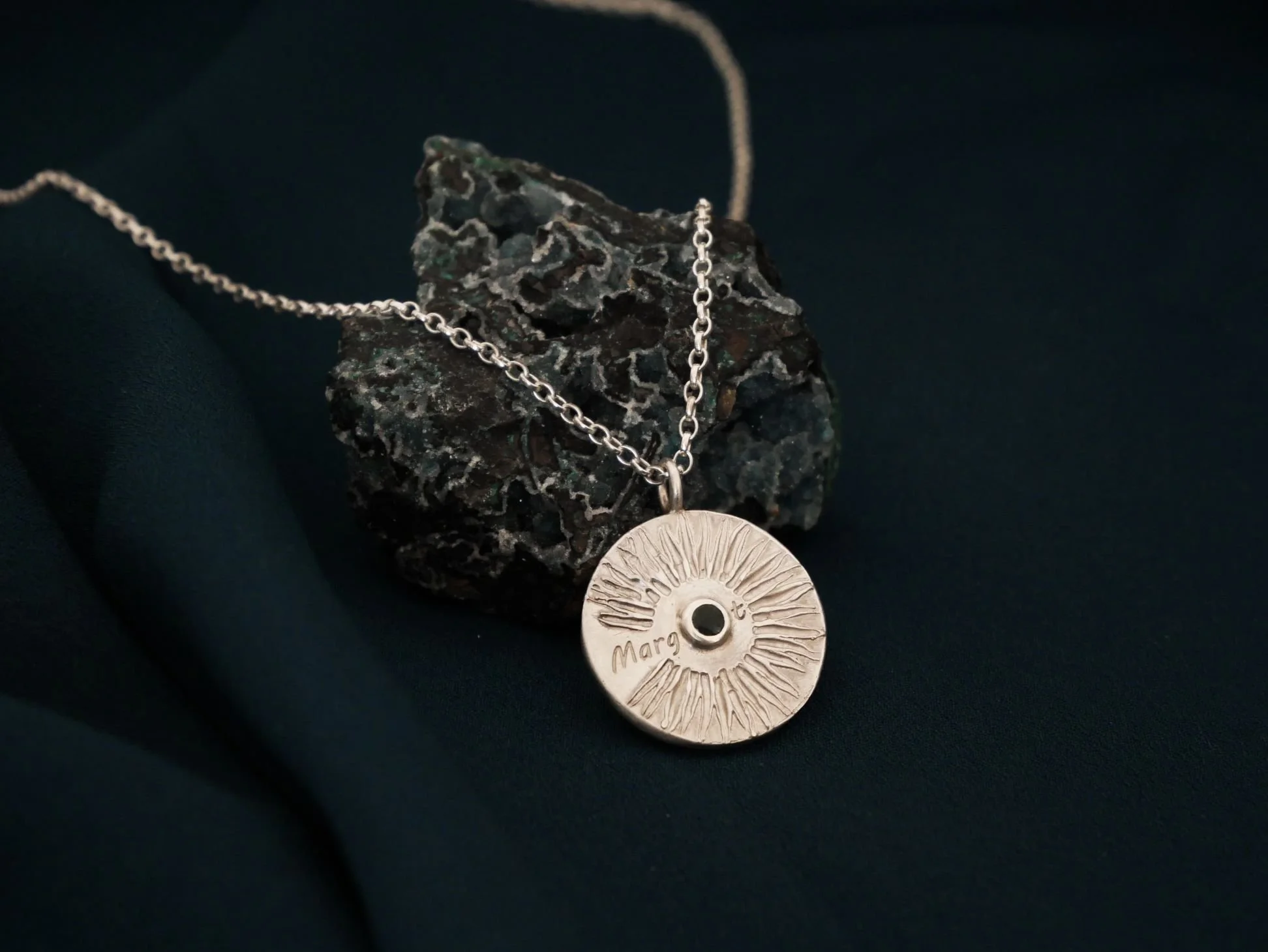 Collier sur mesure avec un prénom gravé et serti d'une pierre verte.