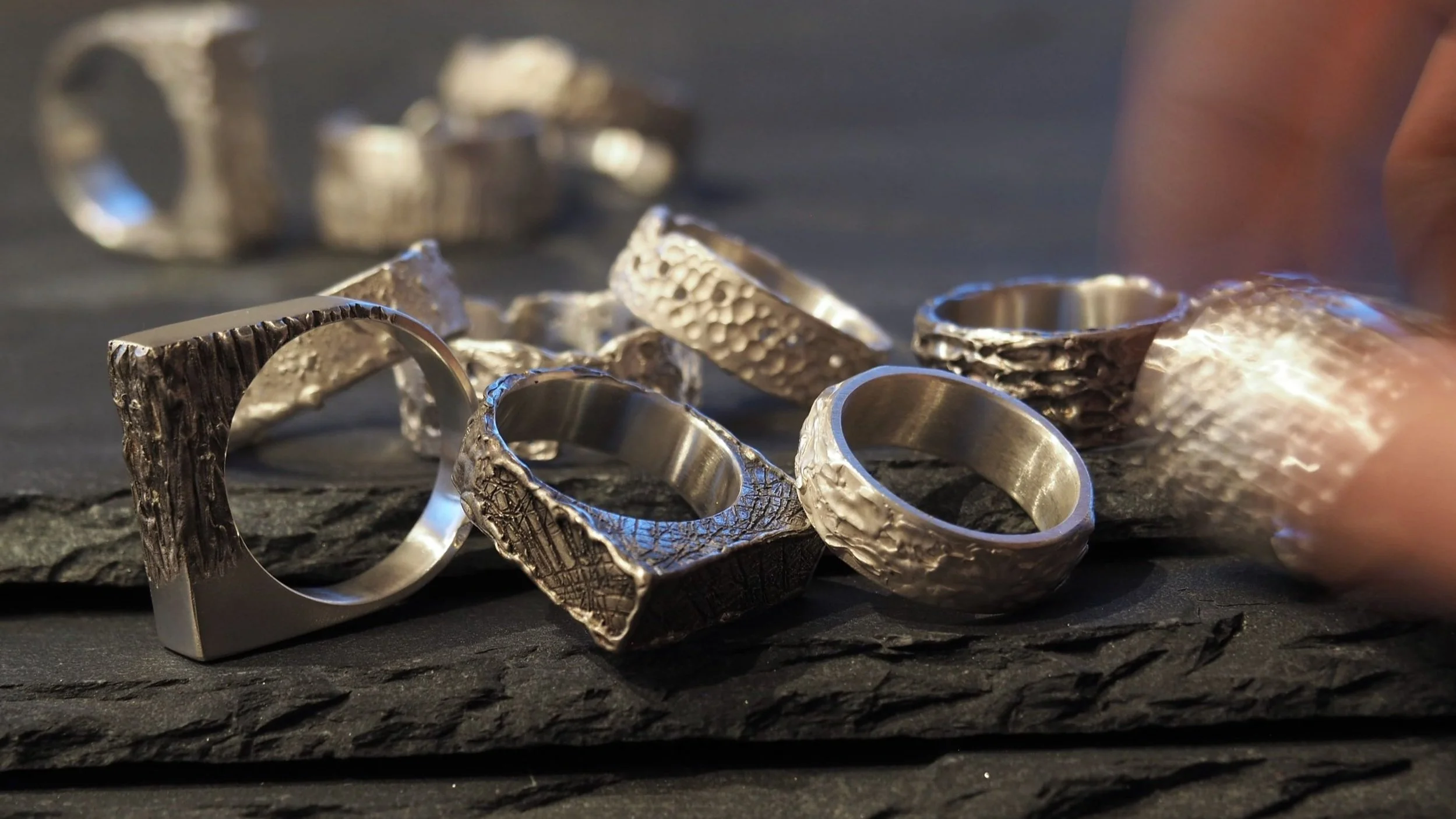 Plusieurs bagues en argent mixtes pour hommes et femmes : carrées, anneaux, mat ou oxydé. Collection variée de bagues artisanales en argent massif, textures uniques pour un style original, avec bague en argent homme et femme large.