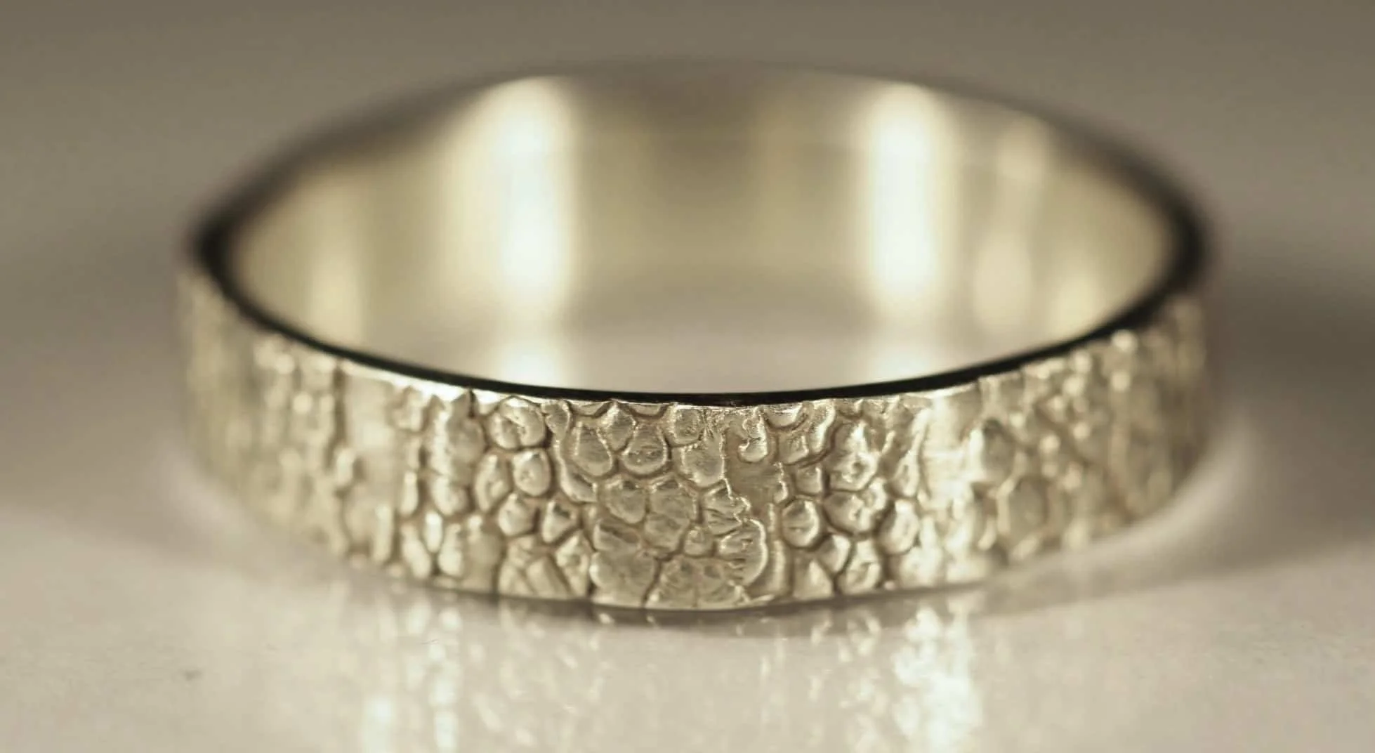 bague empreinte truffe de chien en or blanc sur fond clair. L’empreinte de la truffe du chien recouvre l’entièreté de l’anneau. Cette bague truffe de chien 9 carats est un bijou raffiné et élégant.