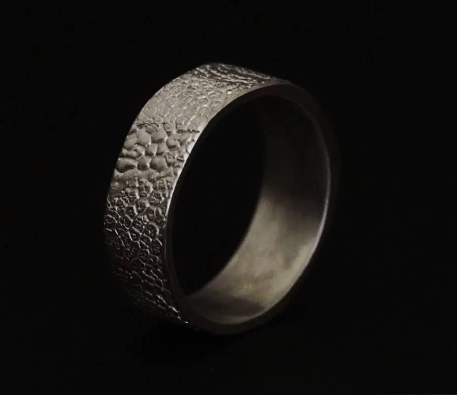 bague truffe de chien en argent sur fond noir. C’est une bague avec l’empreinte de deux chiens. Les bijoux truffes sont une bonne idée de cadeau pour les amoureux des chiens.