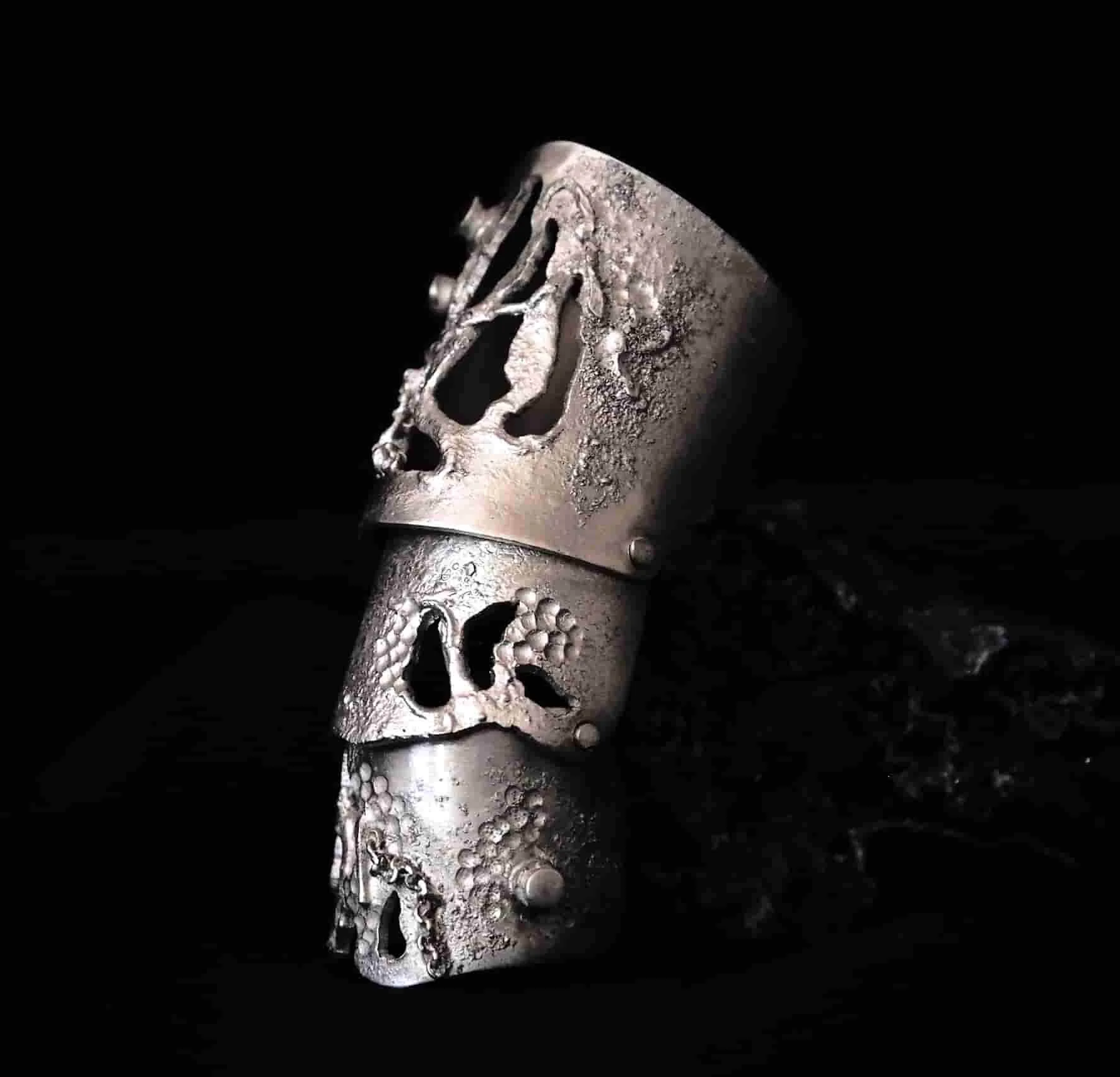 Bague armure en argent sur fond noir.