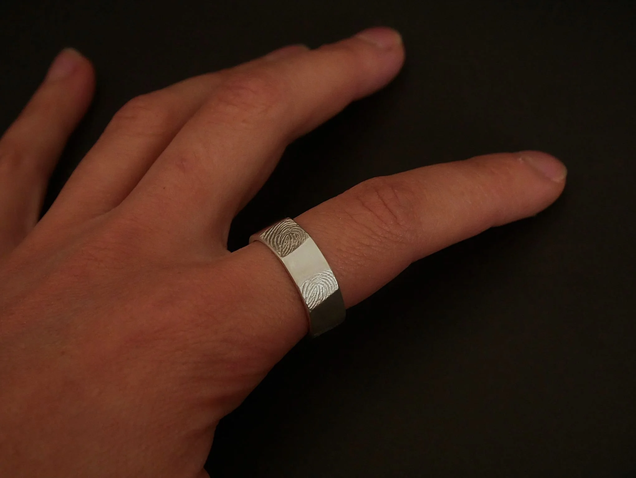Bague empreinte digitale en argent portée sur main de femme, rebord lisse et design élégant, bijou empreinte sur-mesure et sentimental Atelier 962°, symbole d’amour, d’émotion et de lien.