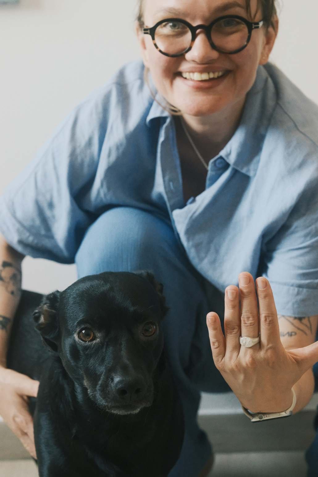 Une femme qui pose fièrement avec son chien en montrant sa main sur laquelle elle porte une chevalière truffe de chien.