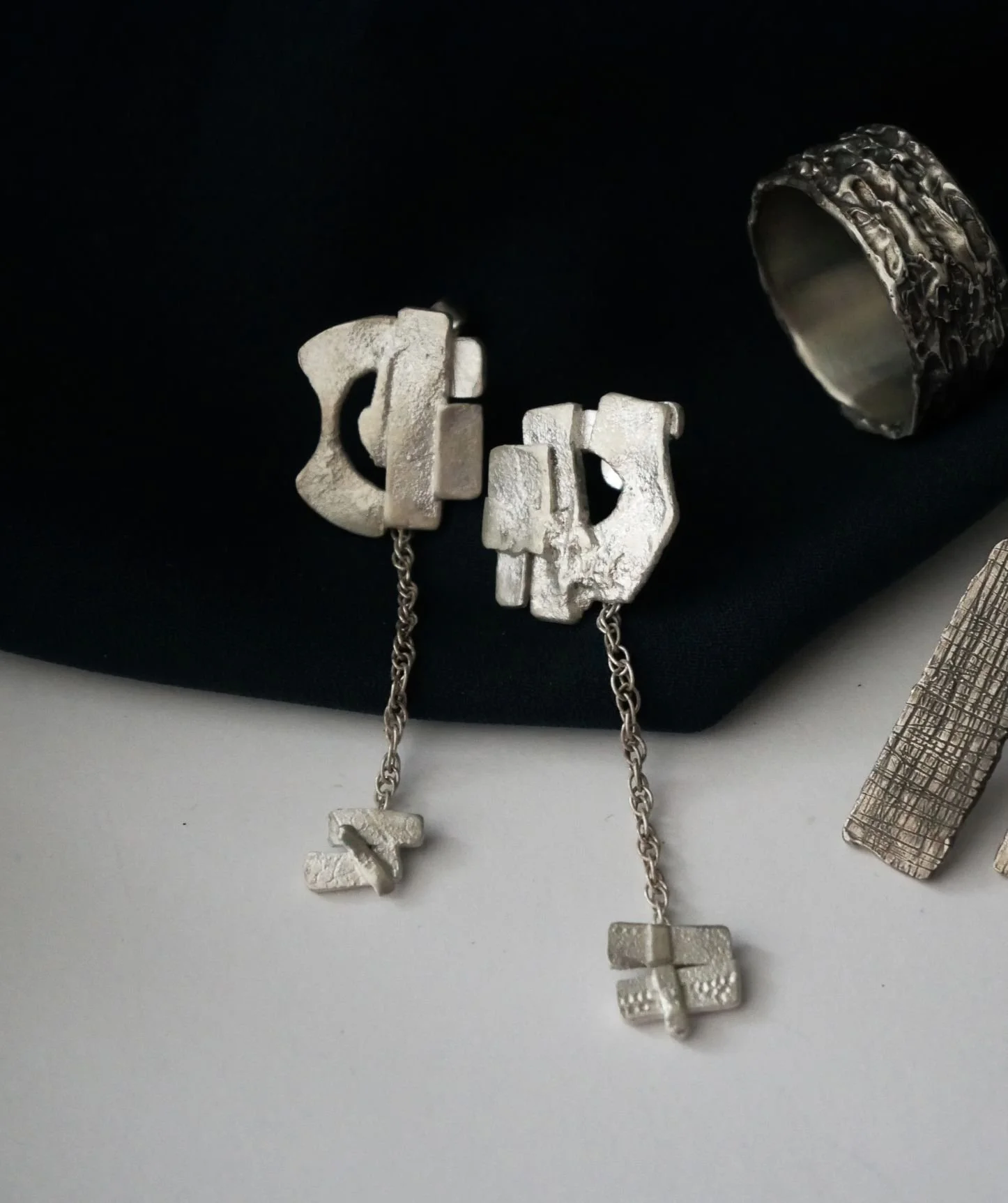 Boucles d'oreilles pendantes en argent recyclé sur fond noir. 