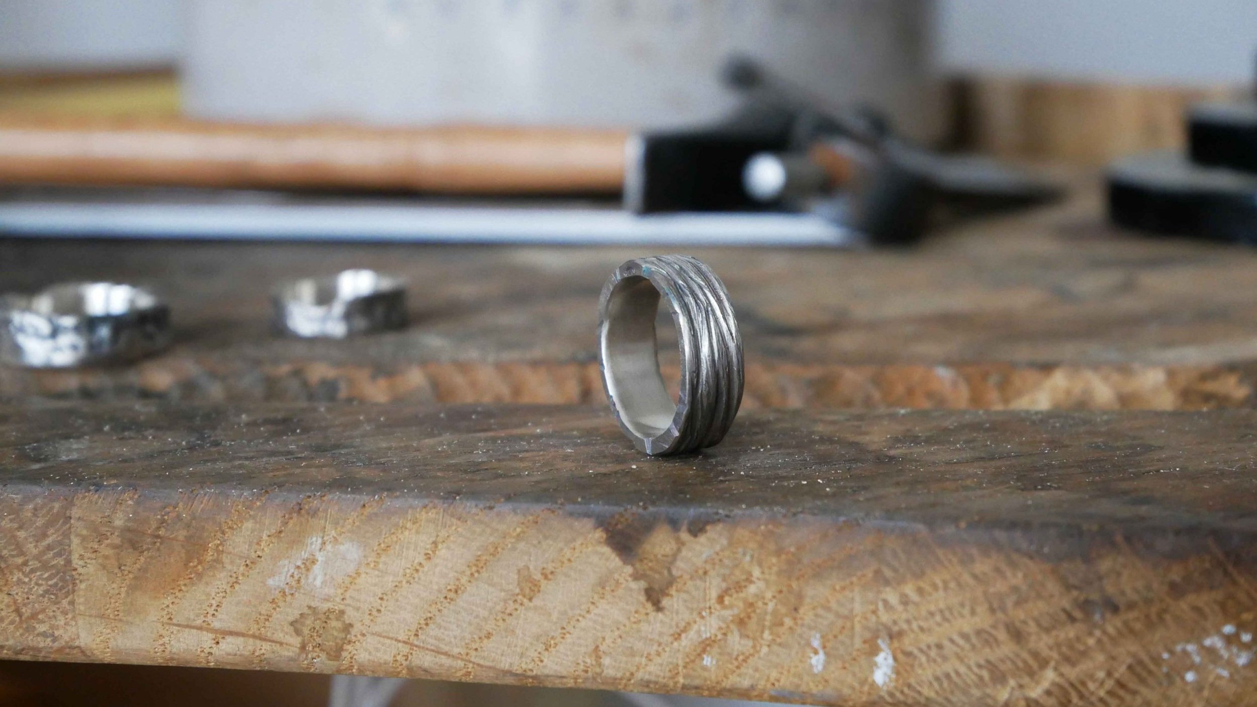 Bague anneau en argent massif fabriquée à la main, posée sur l’établi de la bijoutière. Pièce artisanale authentique en argent 925.