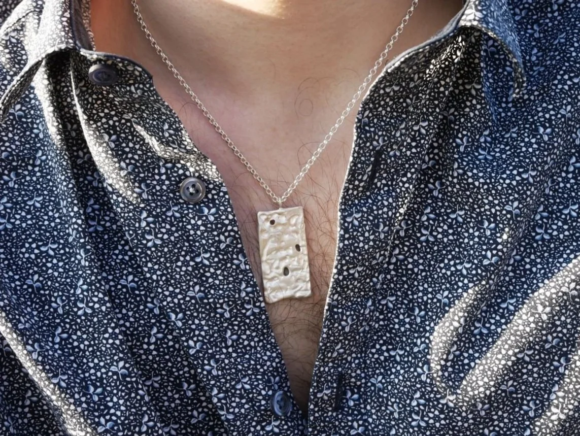 Collier rectangulaire ajouré en argent porté autour du cou d’un homme. Pièce masculine texturée en argent massif 925, style épuré et robuste.