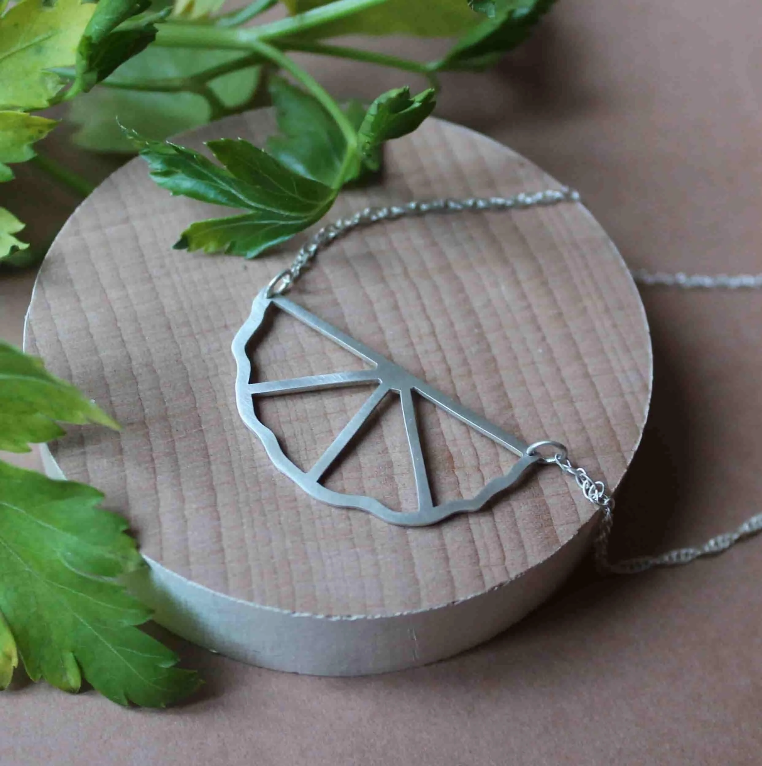 Collier en argent sur mesure, inspiré de formes végétales stylisées. Bijou géométrique ajouré de quatre triangles, au design minimaliste et léger, jouant sur le vide et l’élégance pour une création unique et symbolique.