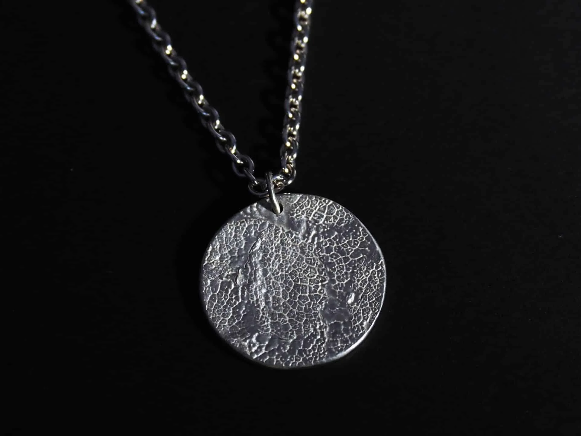 collier empreinte truffe de chien sur fond noir. Le collier museau de chien est en argent avec des finitions mates.