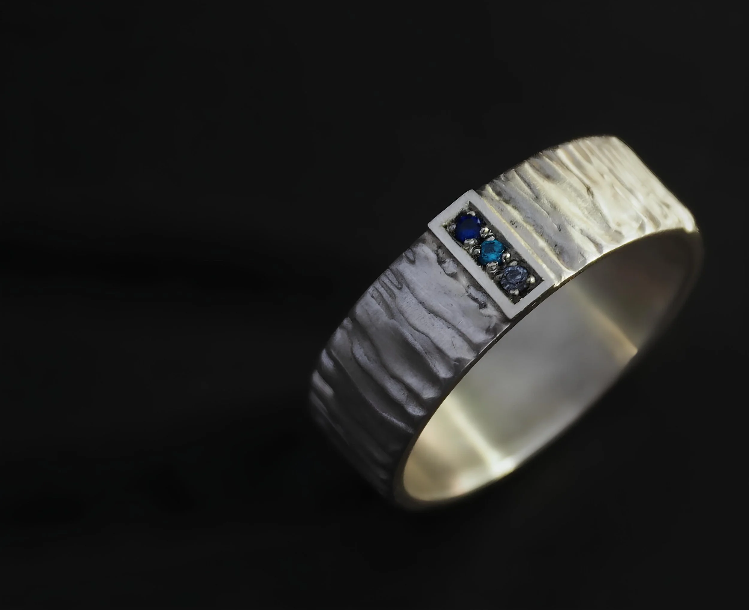 Bague mixte et originale, sertie de pierres bleues.