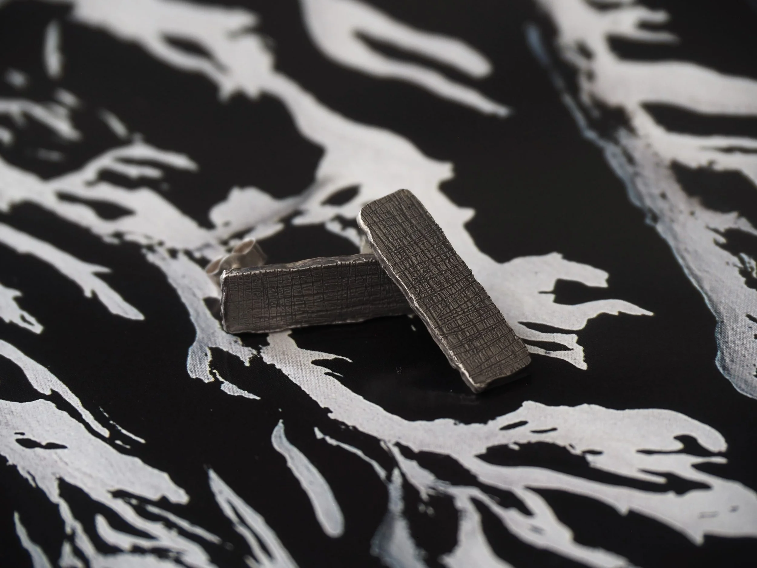 Paire de boucles d’oreilles rectangulaires en argent massif sur fond noir et blanc.