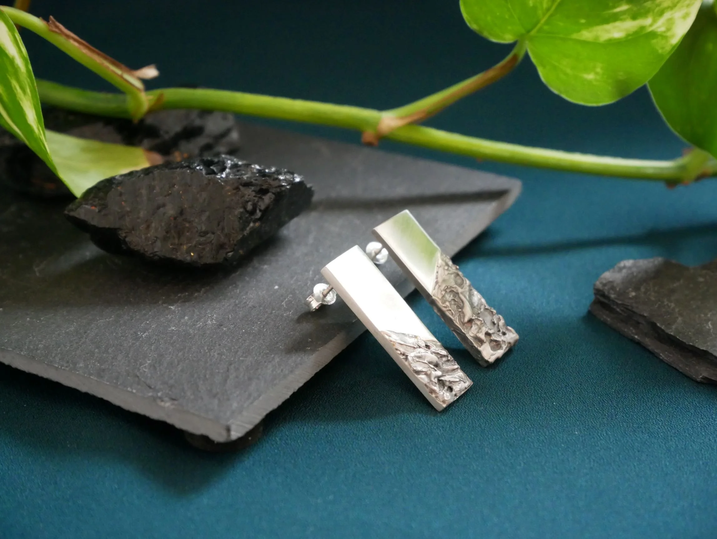 Boucles d’oreilles rectangulaires en argent : lisse poli et texturé oxydé, sur ardoise fond bleuté. Bijoux mixtes aux contrastes subtils.