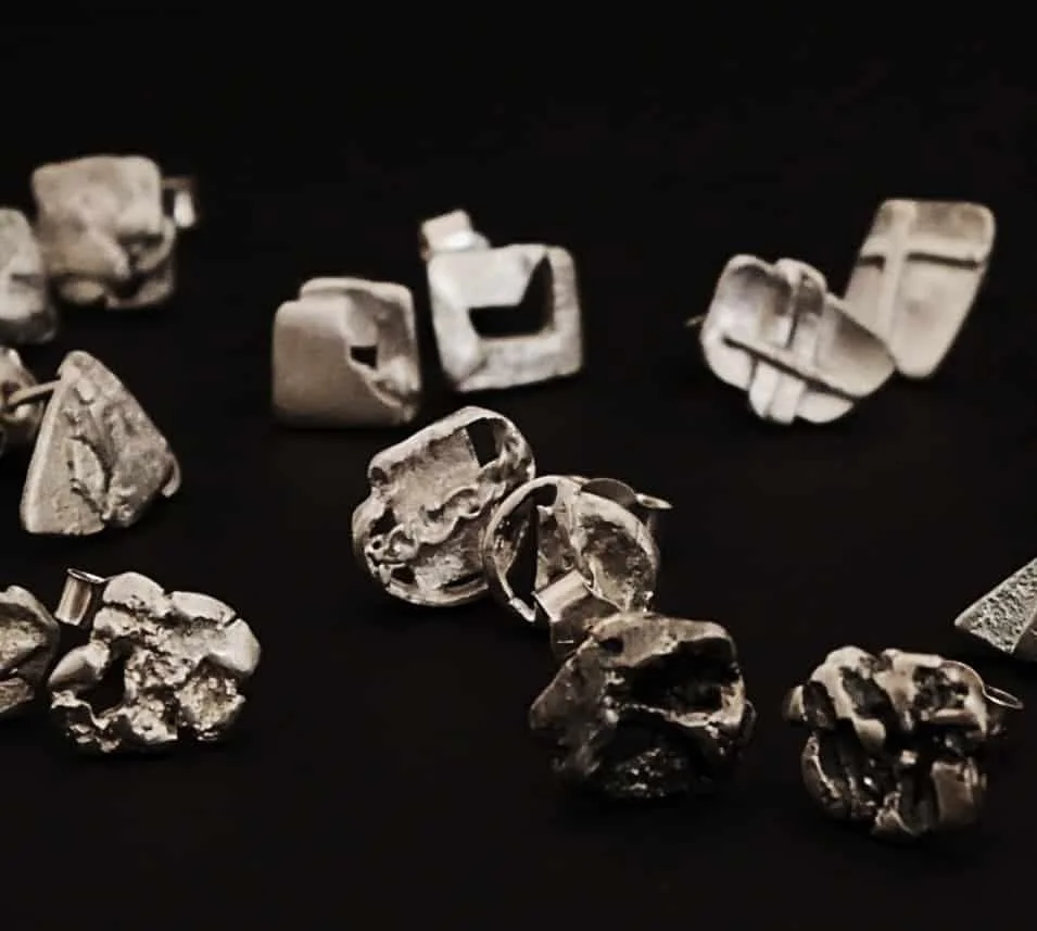Boucles d'oreilles puces en argent recyclé sur fond noir. 