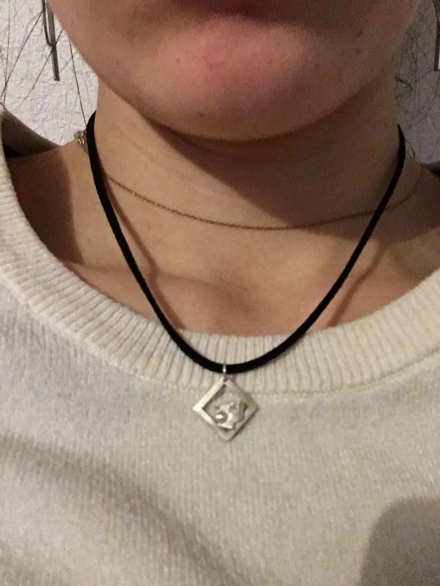 Collier avec pendentif en argent recyclé et chaîne en cuir, porté sur un pull beige. Le bijou pend naturellement sur le décolleté, création artisanale issue d’un atelier de bijouterie à Lyon.