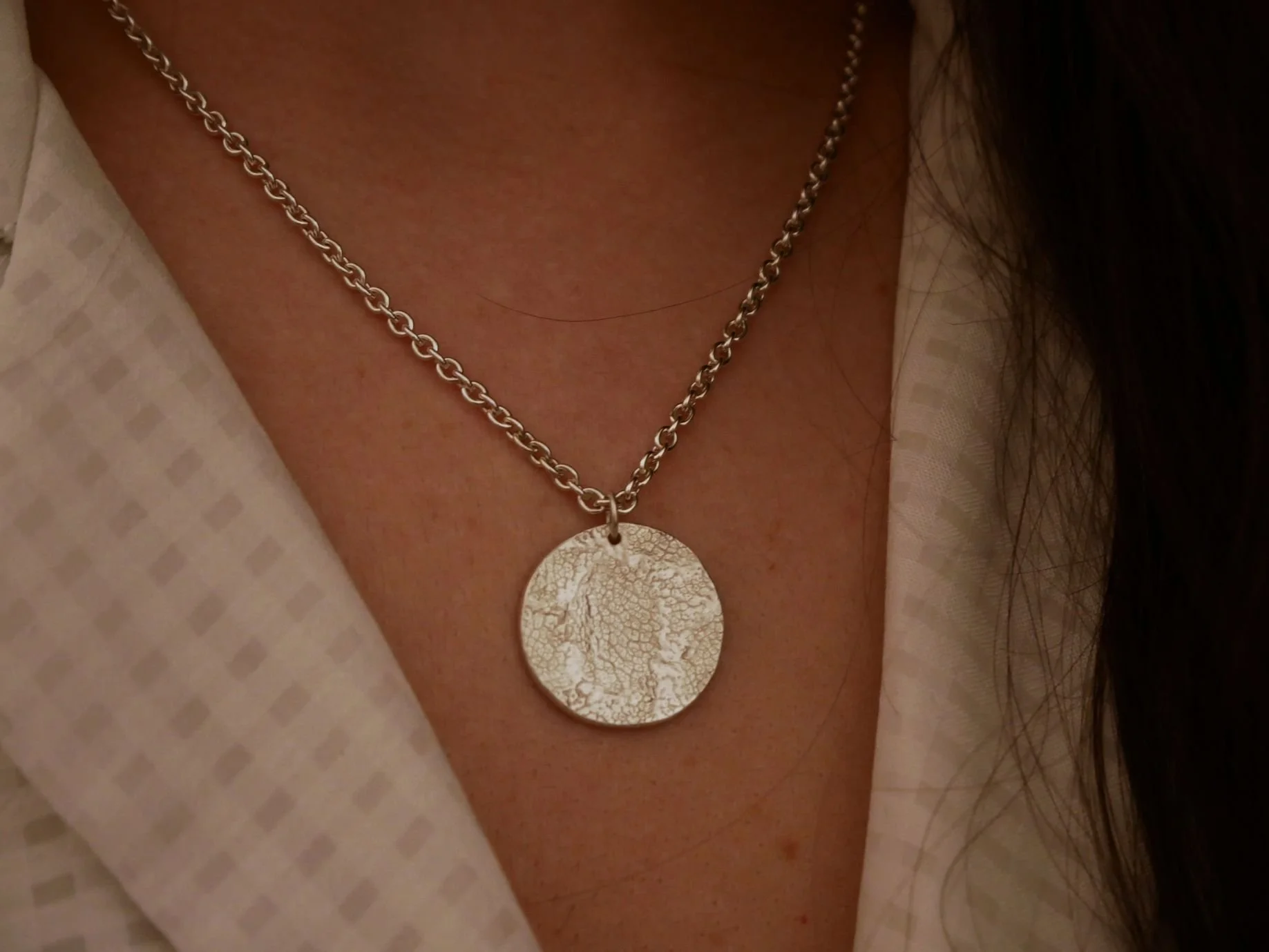 Collier empreinte truffe chien en argent porté autour du cou de sa maîtresse. La finition mate met en valeur l’empreinte du museau du chien sur ce bijou souvenir.
