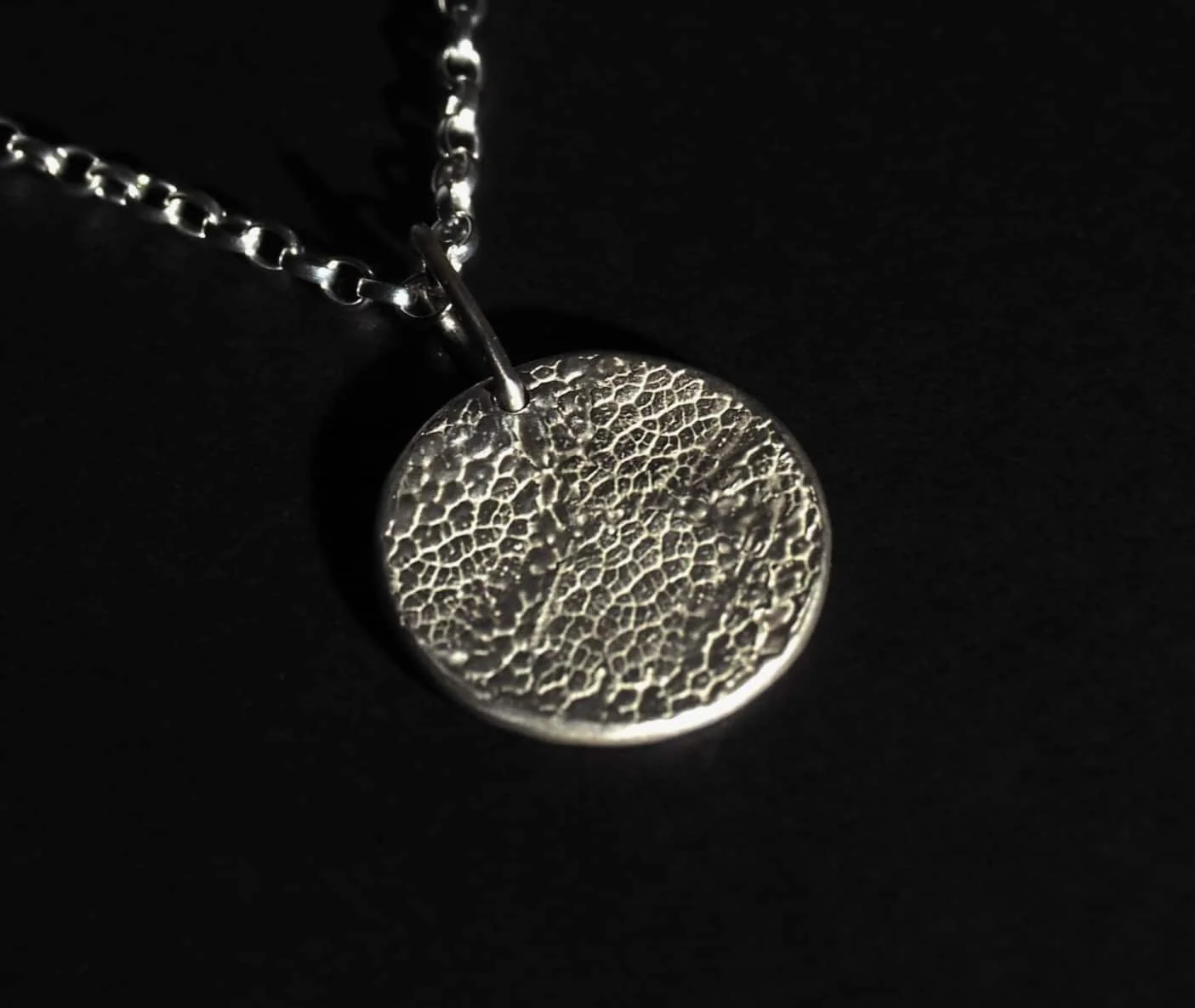 un pendentif avec l'empreinte d'une truffe de chien sur fond noir.