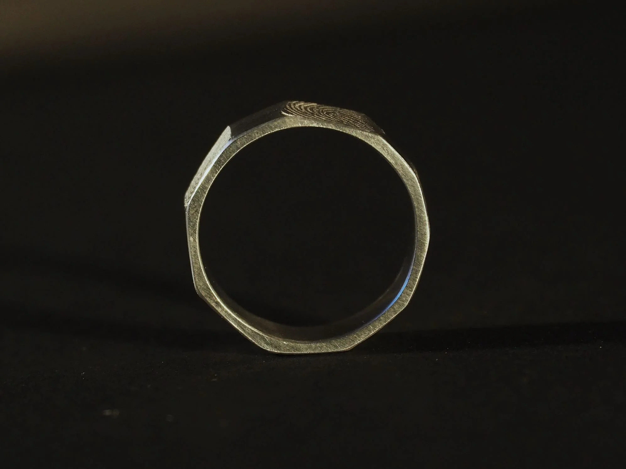 Coupe transversale d’une bague empreinte digitale en argent à rebord lisse, bijou sur-mesure Atelier 962°, travail d’artisan bijoutière lyonnaise révélant la gravure intérieure unique.