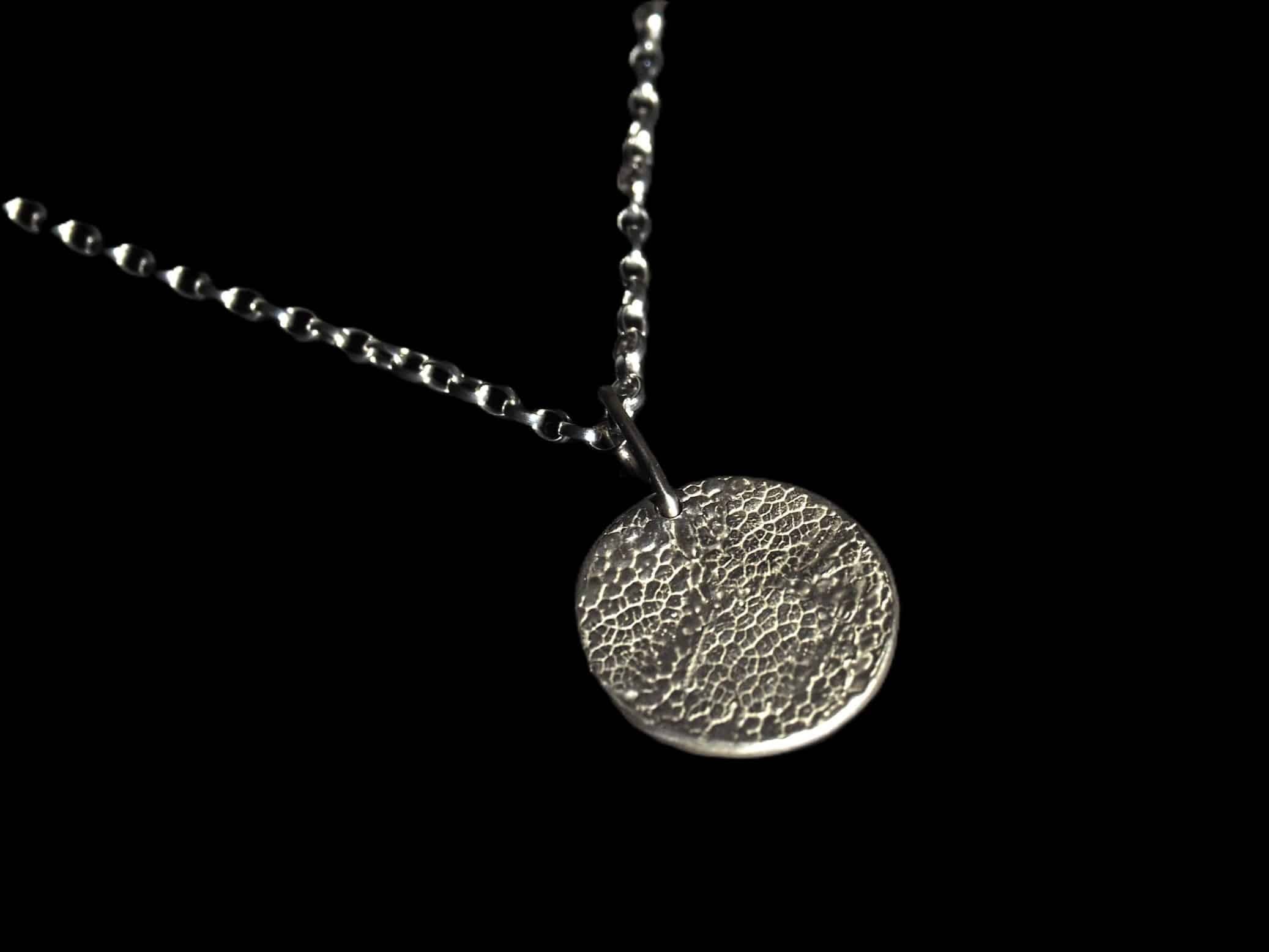 Collier truffe de chien sur fond noir. Le motif de la truffe recouvre toute la surface du médaillon.